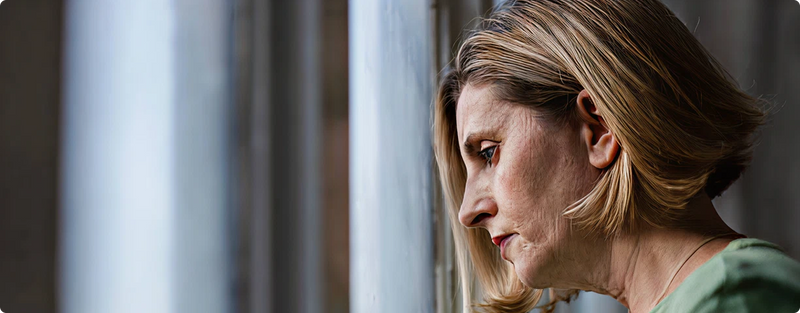 Woman looking out a window with a contemplative expression