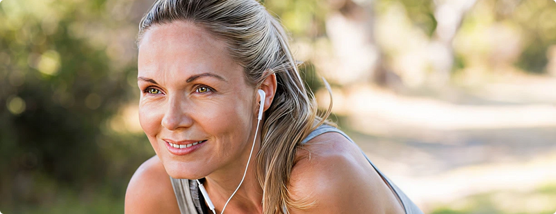 Woman with earphones outdoors, smiling